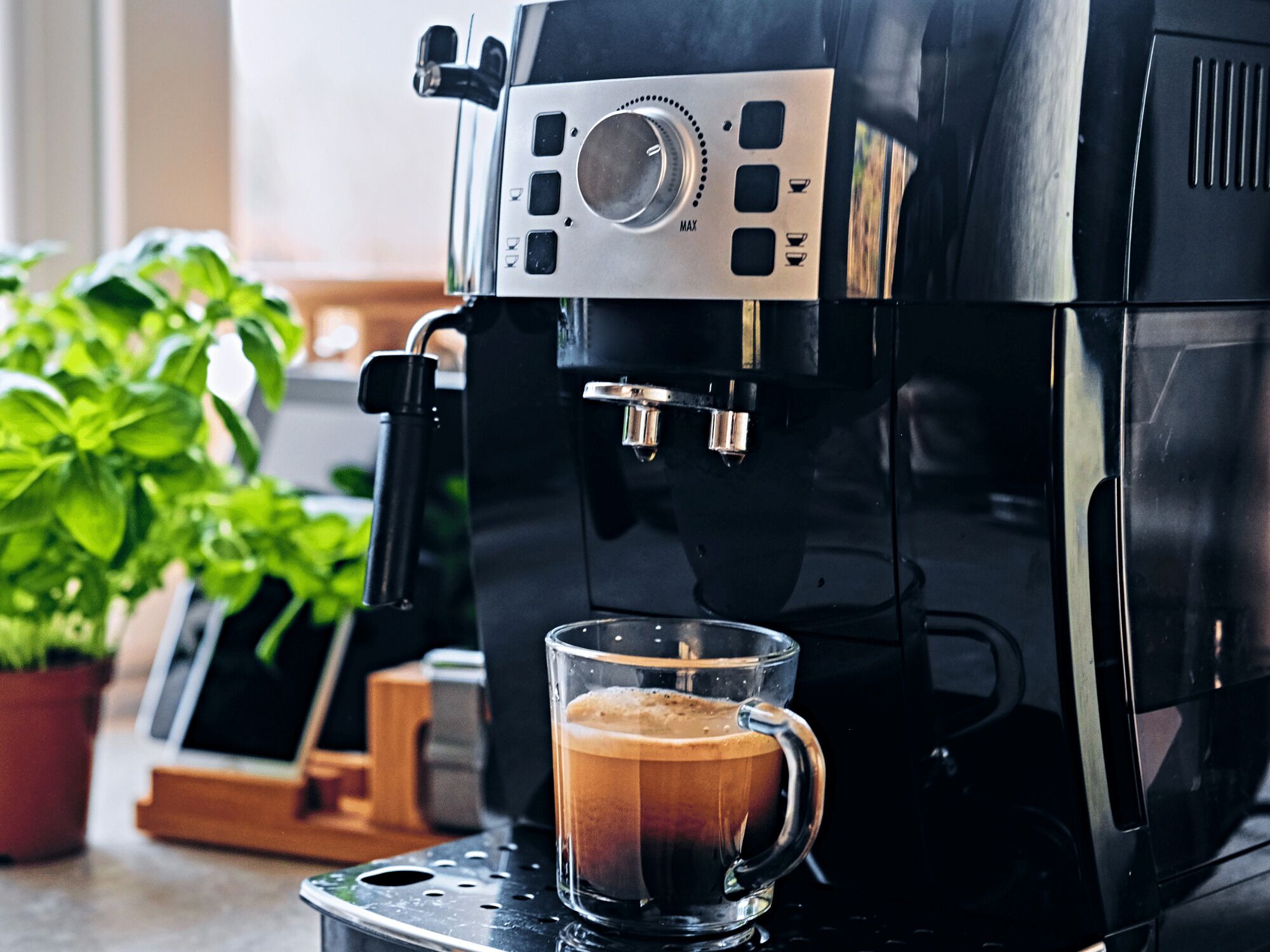 Une machine à café verse du café dans une tasse en verre.