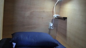 A single bed with a blue mattress and pillow in a room with wooden walls and a wall-mounted light fixture. - chambre d'hôte TATAMI - Hostel (Suwa)