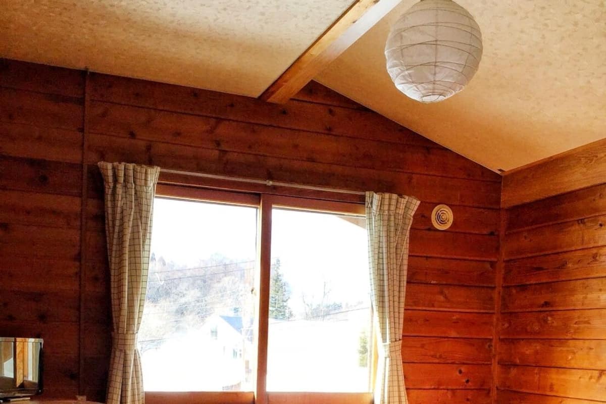 Habitación de cabaña de madera con dos camas, un escritorio y una ventana con cortinas.