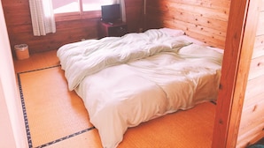 A room with a wooden wall, a bed with white bedding, a small table with a TV, and a window with curtains. - Yado Brodiaea (Myoko)