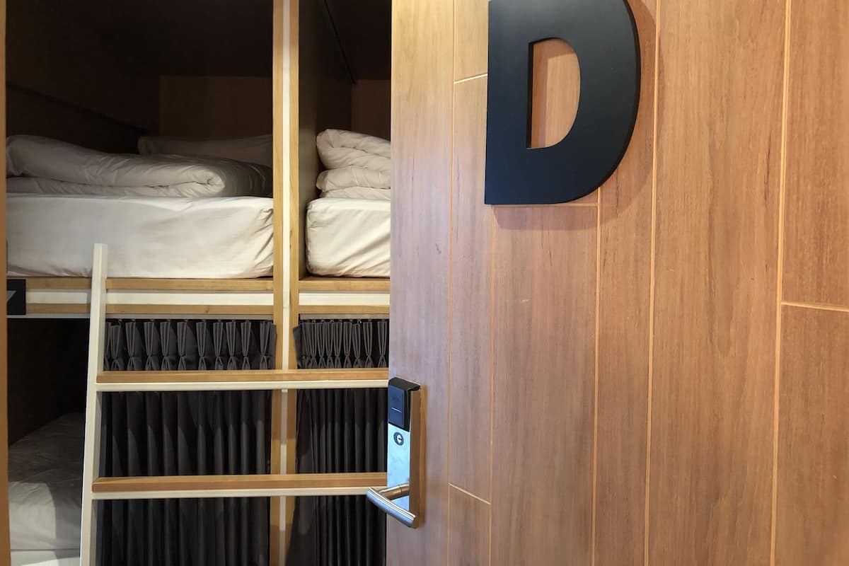 A wooden wall with a large black letter 'D' and a door with a digital lock.