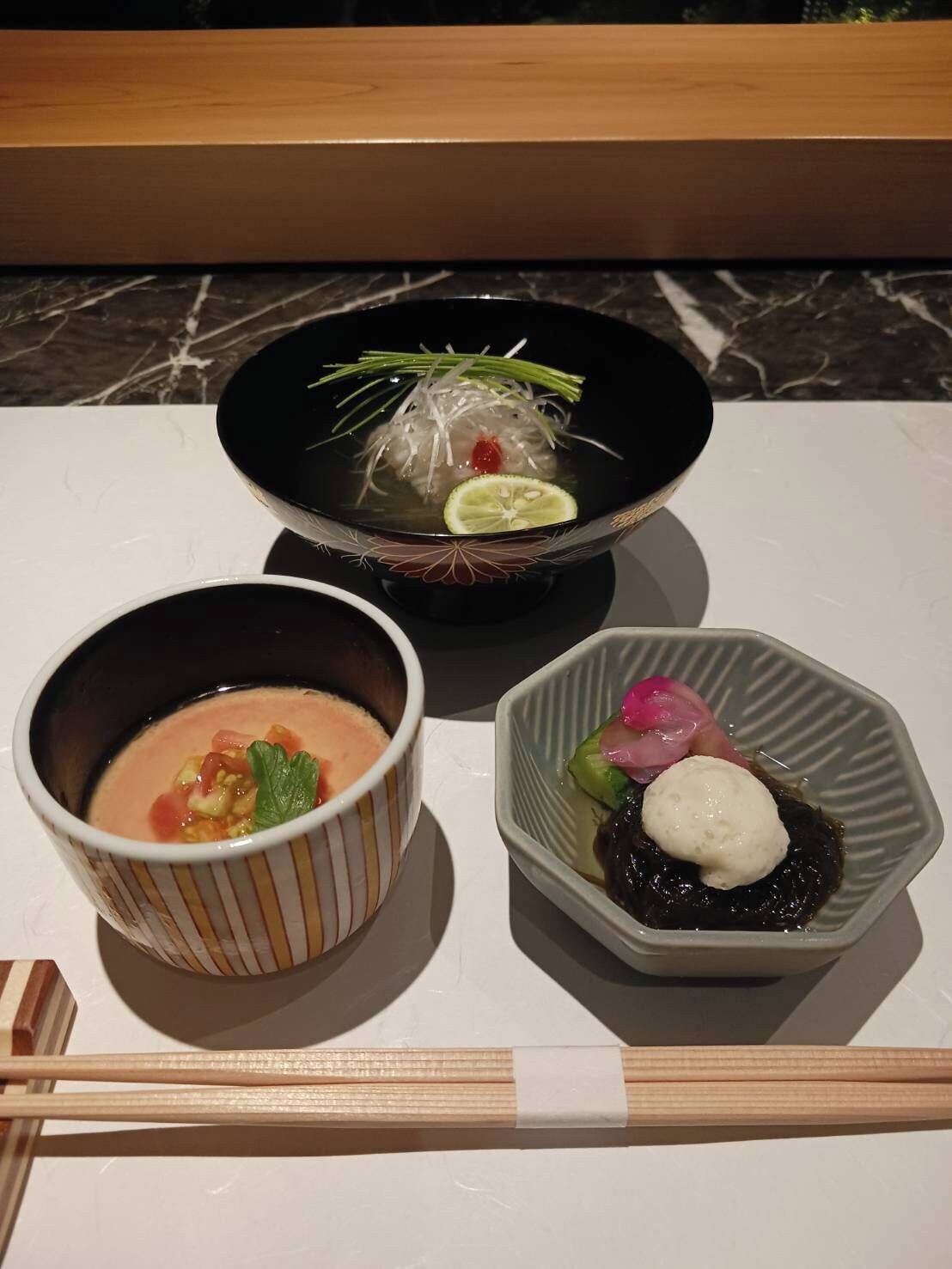 Three dishes on a table with chopsticks in front.
