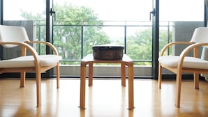 A room with two chairs and a table, large windows with a view of trees, and a door. - Sushi Auberge Gorasaryo (Hakone)