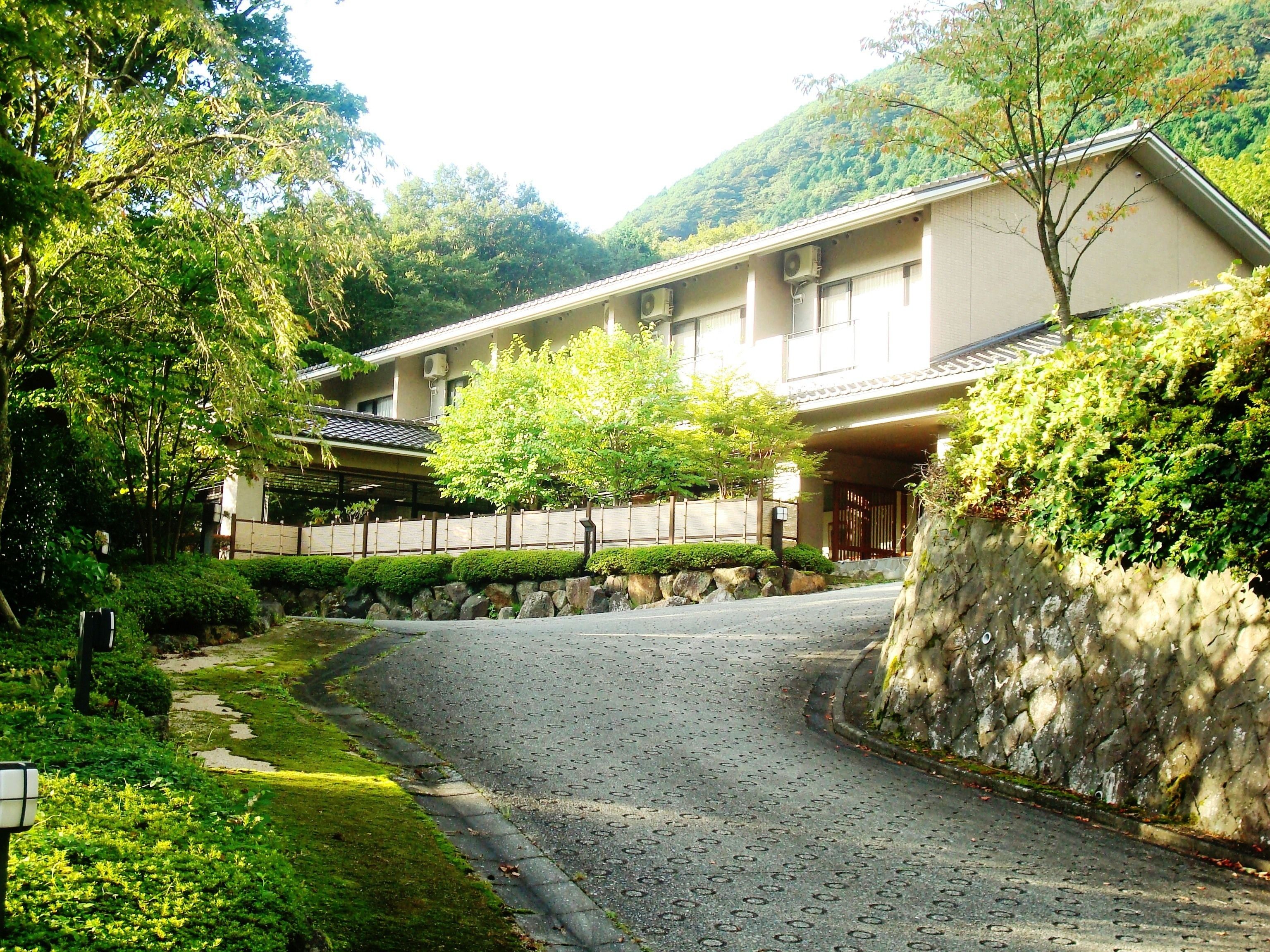 A traditional Japanese building with a gravel driveway leading to a wooden gate.