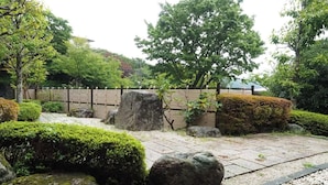 A traditional Japanese garden with stone lanterns, a wooden fence, and well-maintained greenery. - Sushi Auberge Gorasaryo (Hakone)