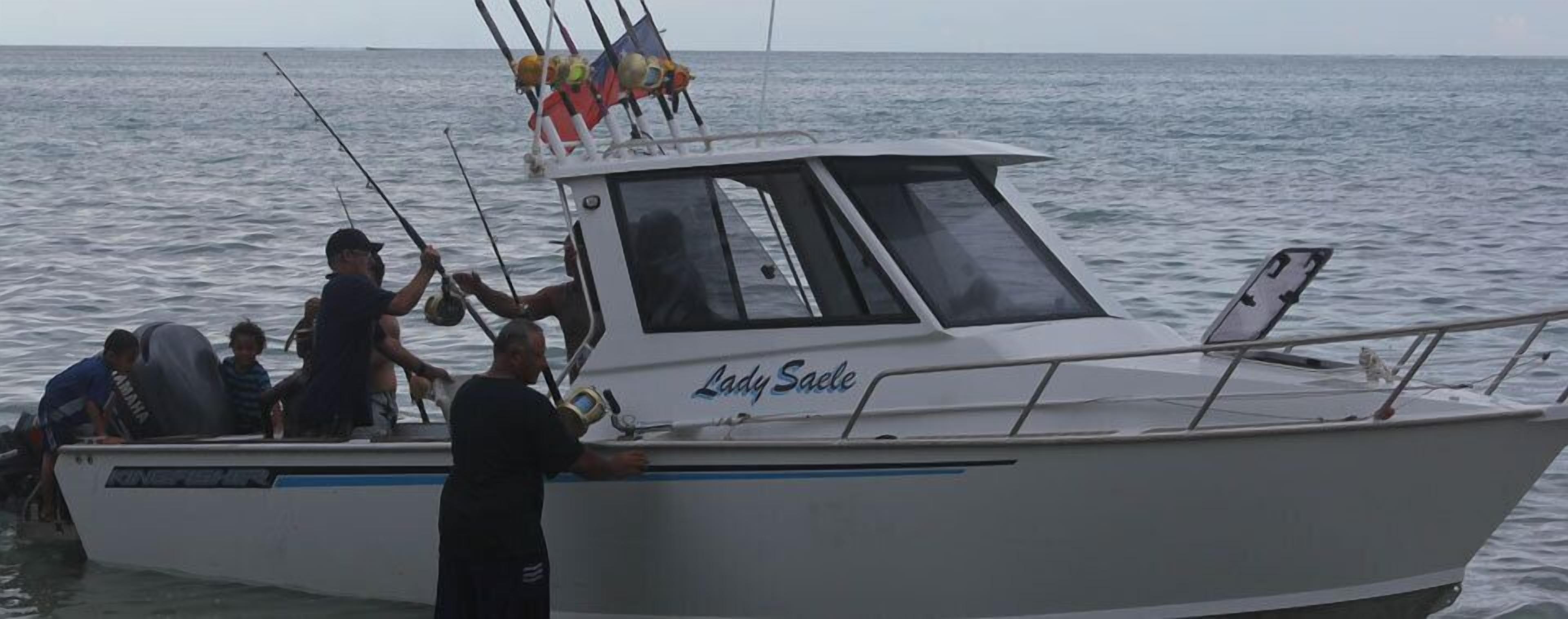 Un bote llamado 'Lady Saele' con camarote, cañas de pescar y una persona de pie en la popa.