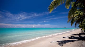 Een privéstrand, wit zand, ligstoelen aan het strand