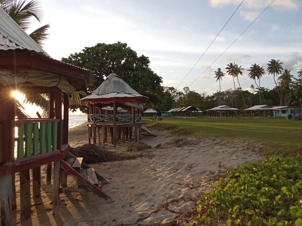 A beachside resort with a gazebo, palm trees, and beach huts.