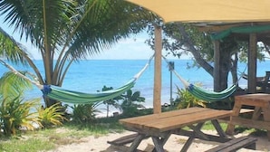 Una estructura de fusta a la vora de la platja, amb una taula, bancs, una cadira llibertat i vista a l'oceà.