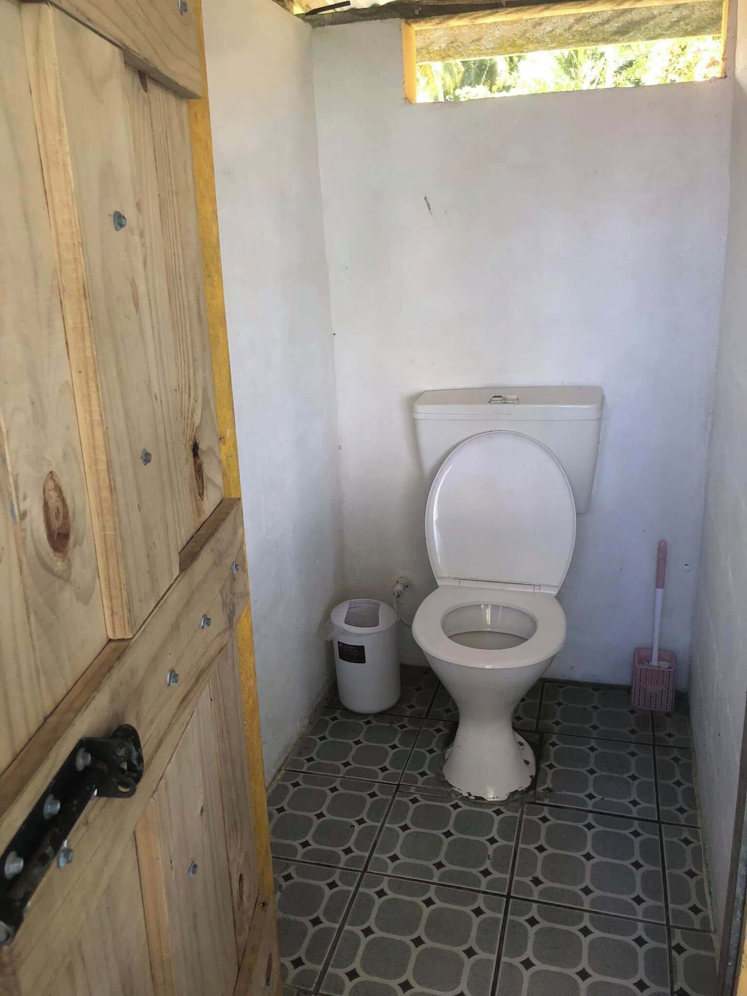 Ein kleines, kompaktes Badezimmer mit Toilette, Mülleimer und Mopp.