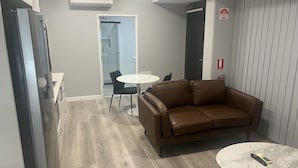 Een moderne kamer met een bruine leren bank, een klein rond tafeltje en een witte stoel.