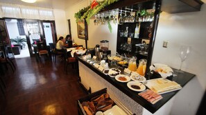 A breakfast buffet with various food items and beverages, a coffee station, and a bar area with bottles and glasses. - Hotel B'liam (Tumbes)