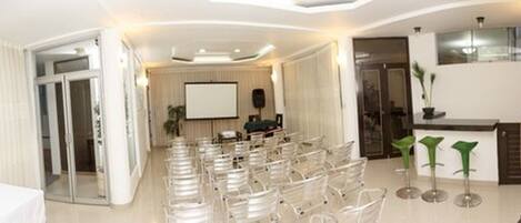A conference room with rows of chairs, a projector screen, and a podium.