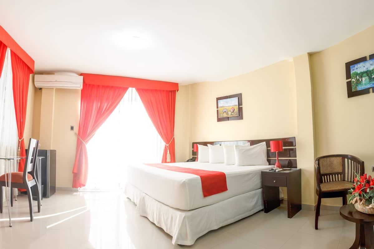 A hotel room with a large bed, a desk, a chair, and a TV.