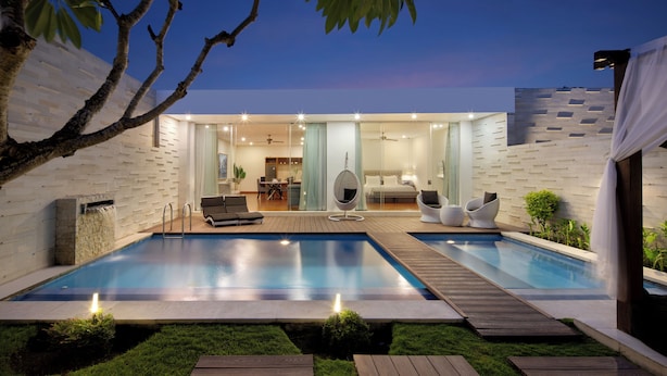 Uma casa moderna com piscina, área de refeições e sala de estar com sofá e cadeiras.