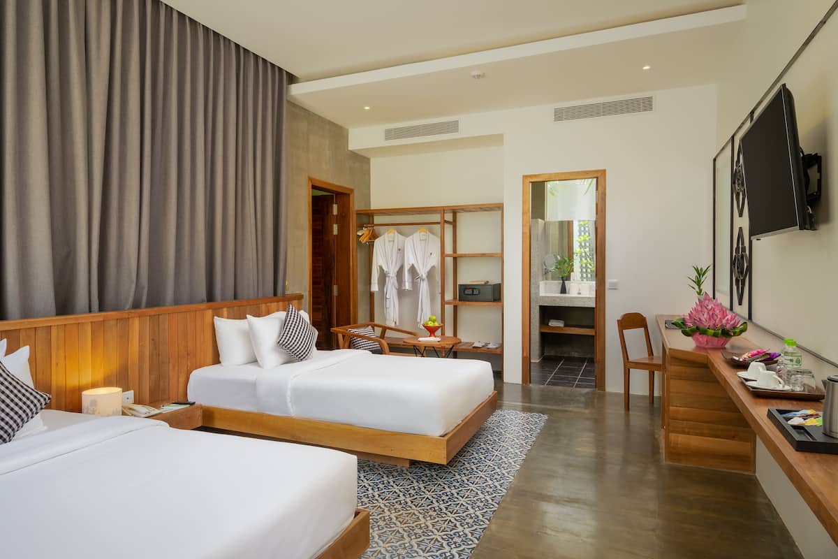 Una habitación de hotel con dos camas, un escritorio, un espejo y un televisor.