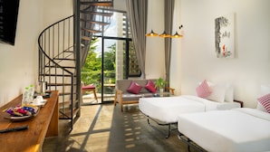 Una habitación de hotel moderna con una escalera espiral, un balcón con vistas, un sofá, una cama y un comedor con mesa de madera.