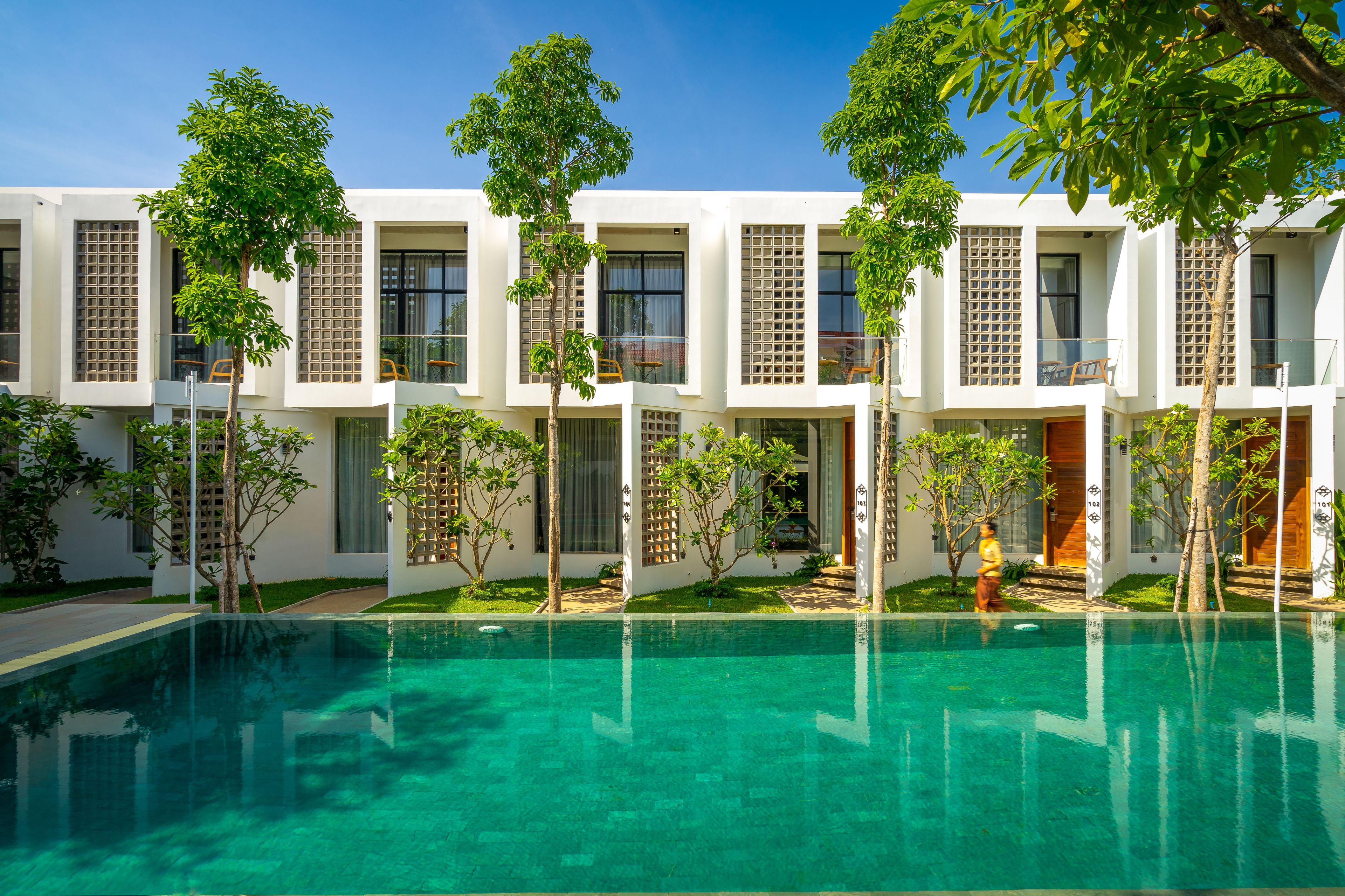 A modern building with a swimming pool, surrounded by trees and greenery.