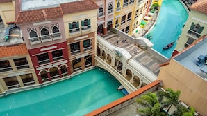 A multi-story building with a central courtyard featuring a swimming pool, surrounded by colorful buildings with balconies and outdoor seating areas. - Venice Mall Area McKinley Hill Taguig BGC (Taguig)