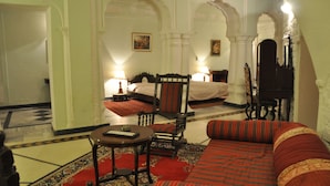 A traditional room with a bed, a sofa, a small table, and a chair. - The Fort Nalagarh (Nalagarh)