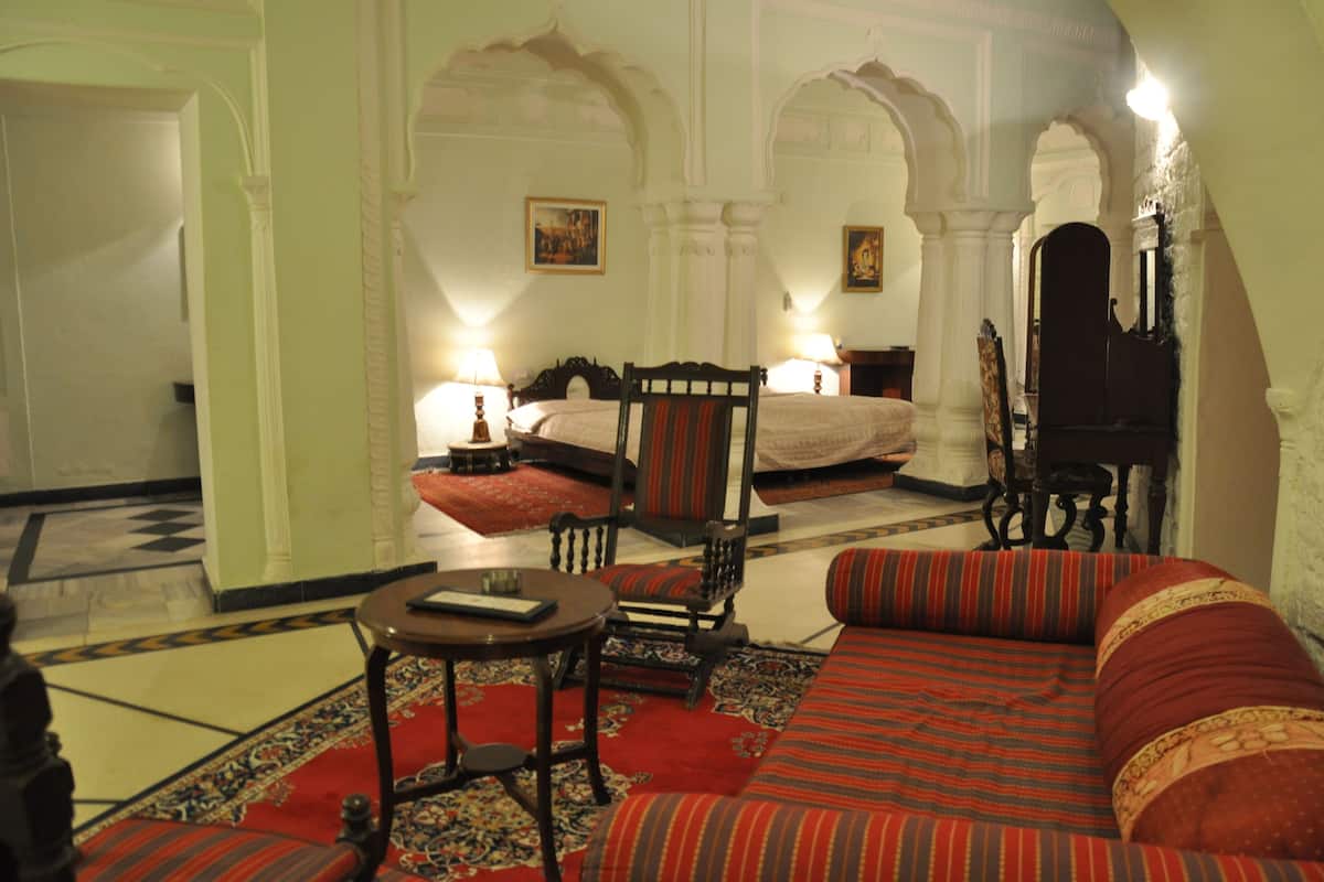 A traditional room with a bed, a sofa, a small table, and a chair.