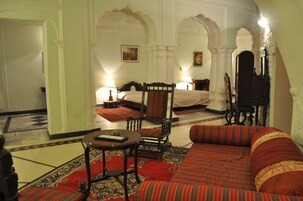 A traditional room with a bed, a sofa, a small table, and a chair.