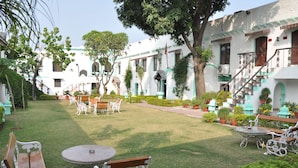 A courtyard with a dining area, benches, and potted plants. - The Fort Nalagarh (Nalagarh)