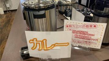 Een aanrecht met een grote, roestvrijstalen slowcooker en een bord met Japanse tekst.