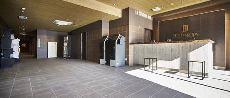A spacious lobby with a reception desk, air conditioning units, and a tiled floor.