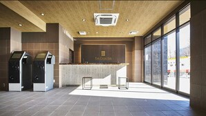 A modern reception area with a wooden ceiling, a reception desk, and two self-service kiosks.