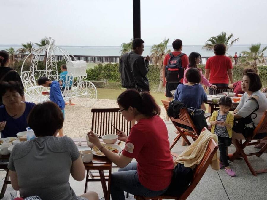 Un grupo de personas cenando al aire libre con vistas al mar.