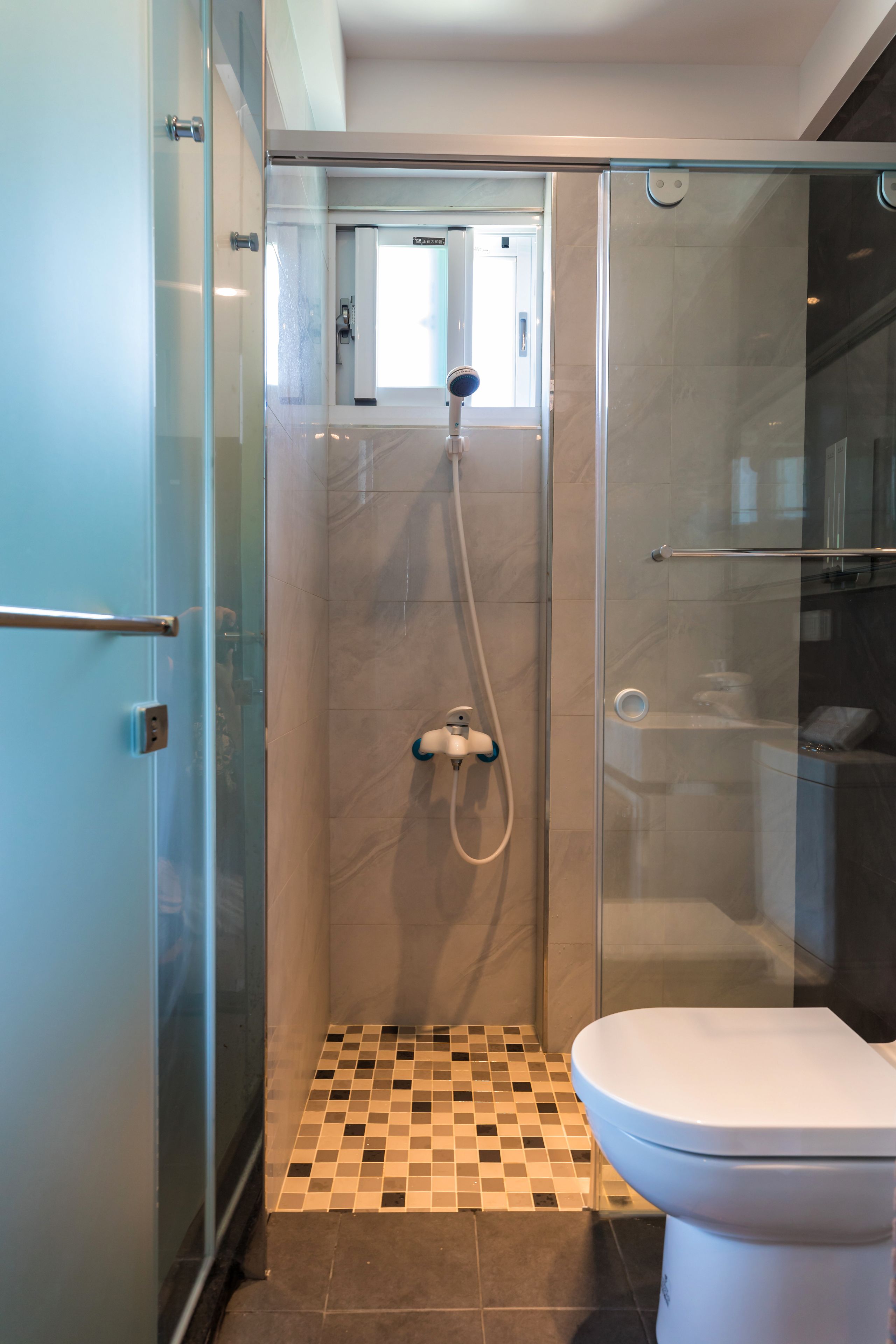 A modern bathroom with a glass-enclosed shower, a toilet, and a tiled floor.