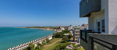 Vista costera desde un balcón con vista a una playa y al océano.