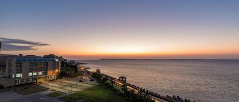 A coastal hotel with a view of the sea at sunset.