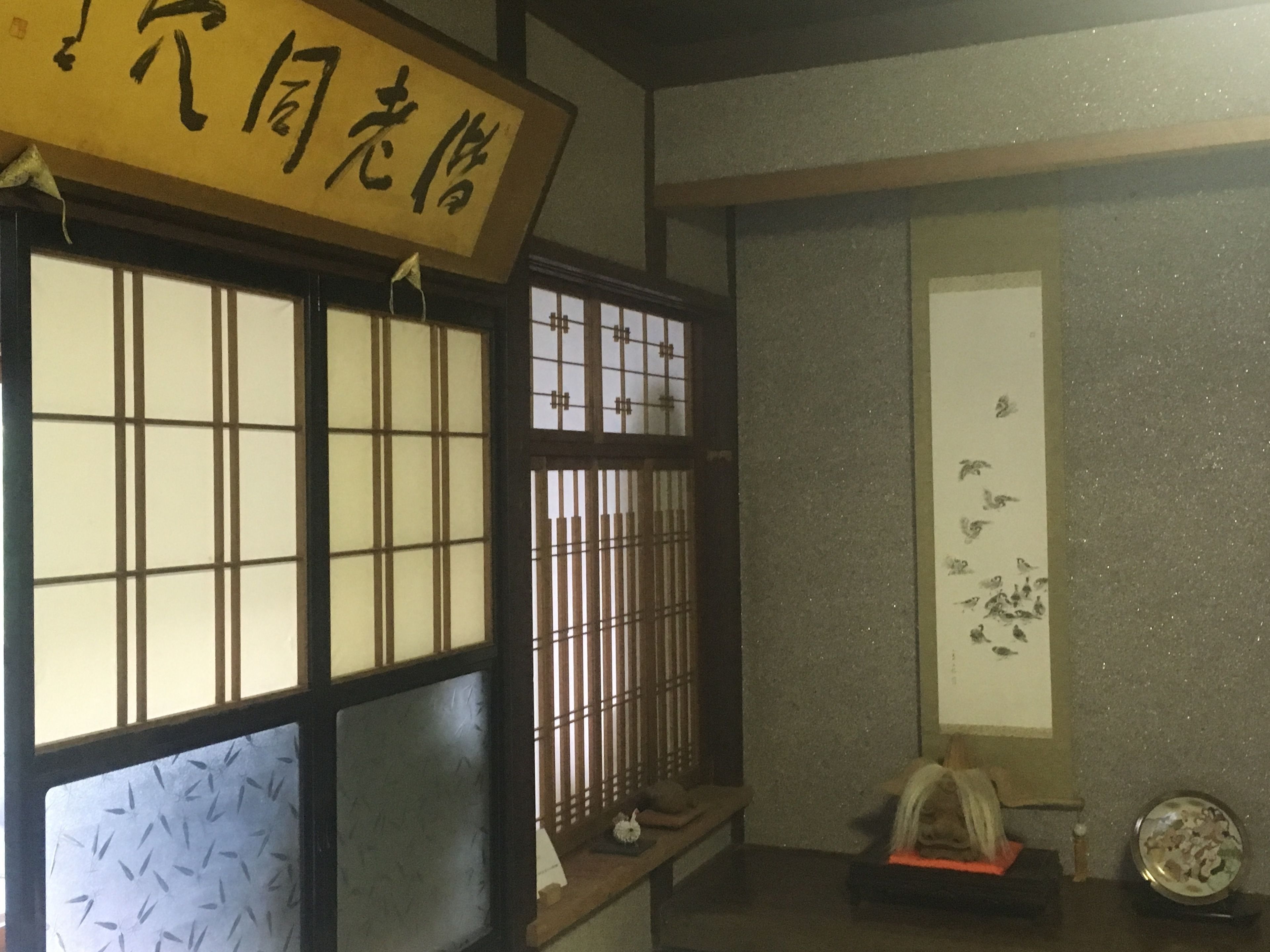 A traditional Japanese room with tatami flooring, shoji screens, and a sliding door.