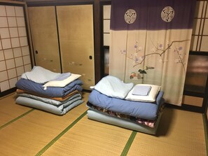 Two futons with pillows, a tatami mat floor, and a shoji screen with a floral design.