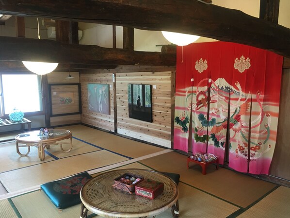A traditional Japanese room with tatami flooring, a low table with a woven top, a cushioned bench, and a sliding door with a floral design.