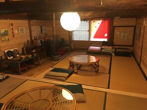 A traditional Japanese room with tatami flooring, a low table, cushions, and various decorative items.