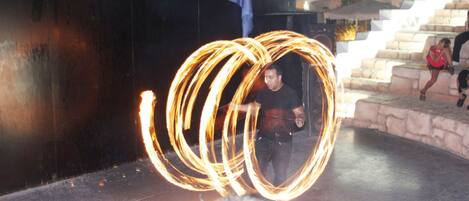 Una persona haciendo malabares con fuego usando un aro grande.