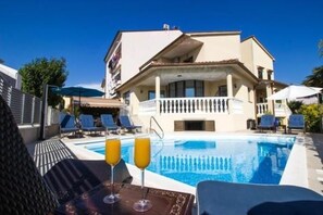 A hotel with a swimming pool, lounge chairs, and umbrellas.