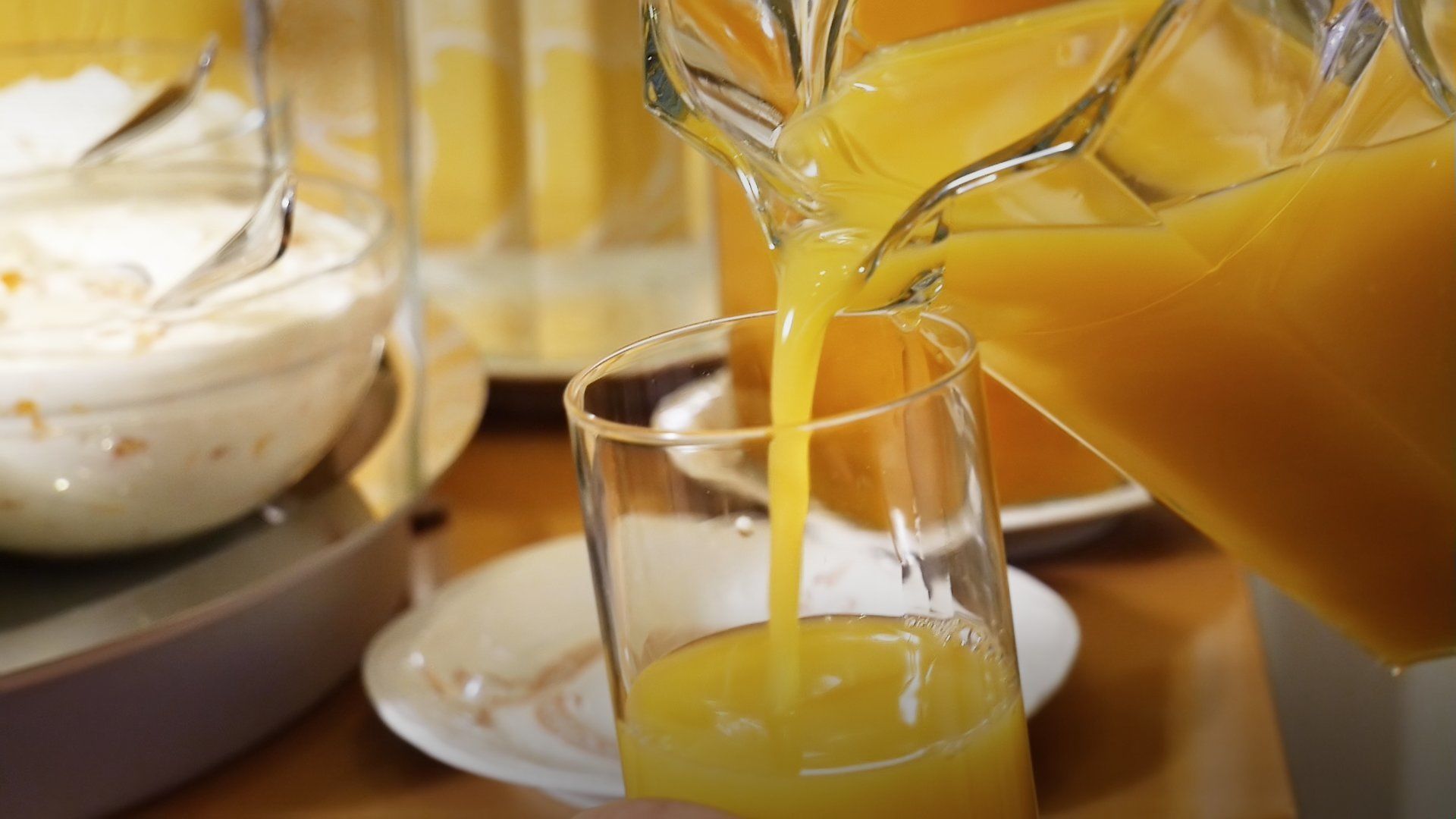 A glass being filled with orange juice from a pitcher.