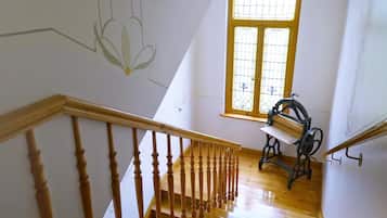 A wooden staircase with a handrail, a window with a yellow frame, and a vintage sewing machine on the landing.