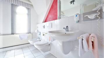A modern bathroom with a toilet, bidet, and sink.