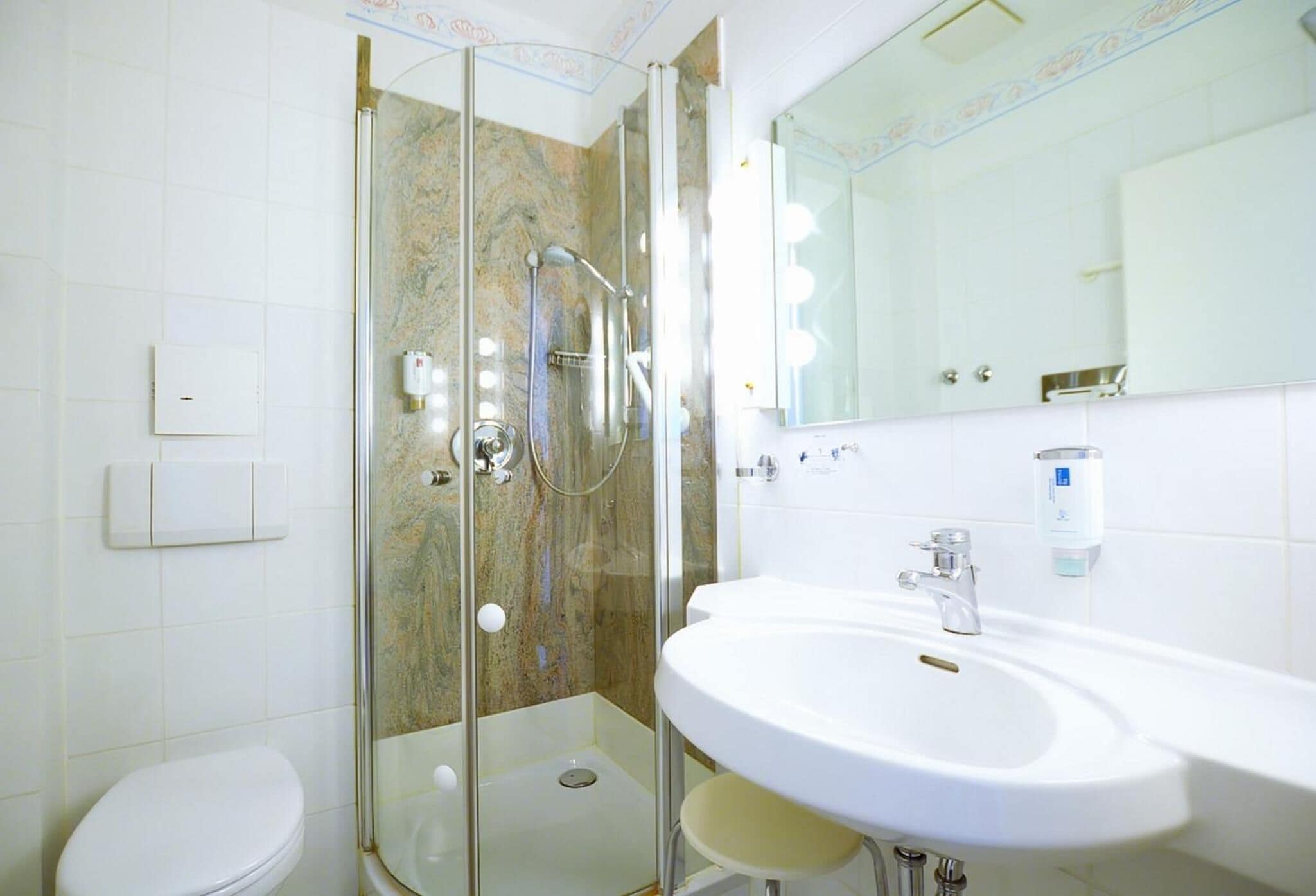 A modern bathroom with a glass-enclosed shower, a white sink, and a toilet.