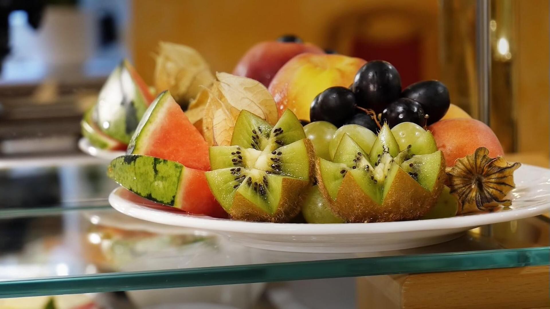 A plate of assorted fruits including watermelon, kiwi, grapes, and peaches.
