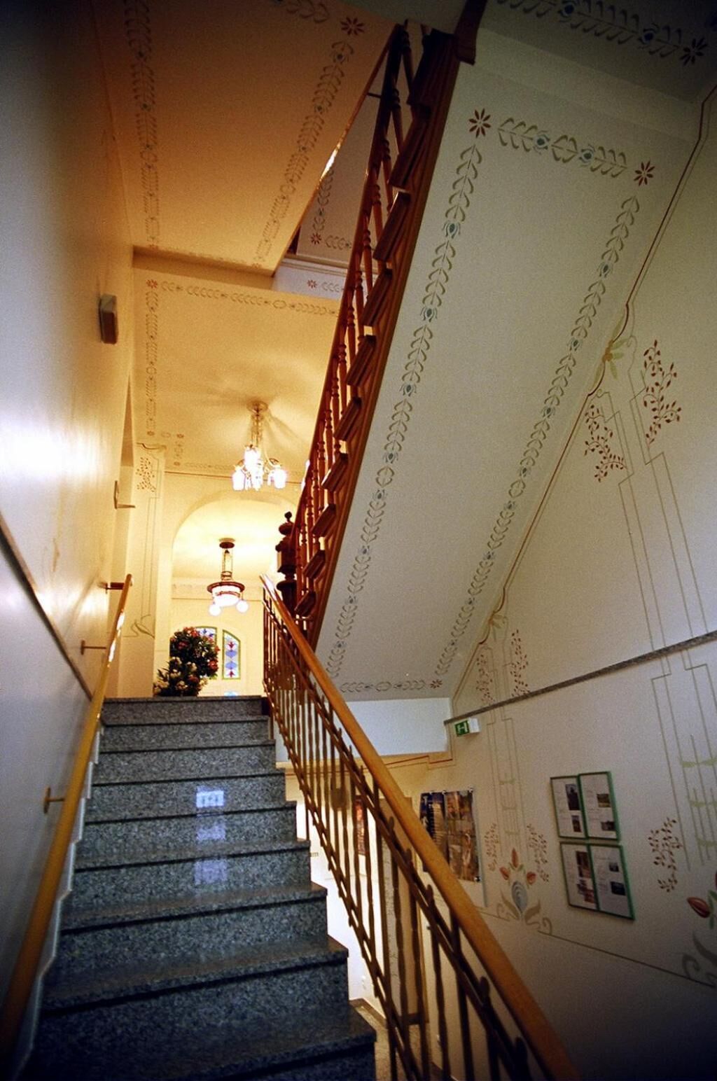 Eine Treppe mit einer Holzhandläufe, einem Kronleuchter und Wandverzierungen.