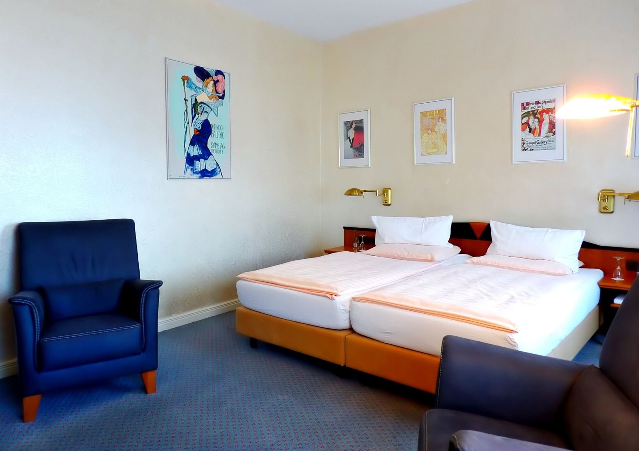 Een hotelkamer met een tweepersoonsbed, twee nachtkastjes, een stoel en een wanddecoratie.