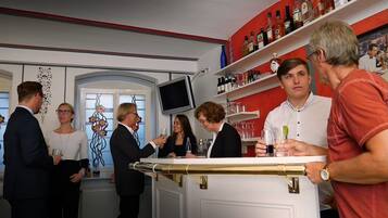 En bar med en disk, hylder med flasker og et fjernsyn.