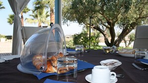 Un espacio para comer al aire libre con un mostrador cubierto de comida, una taza de café y una mesa lista para una comida.