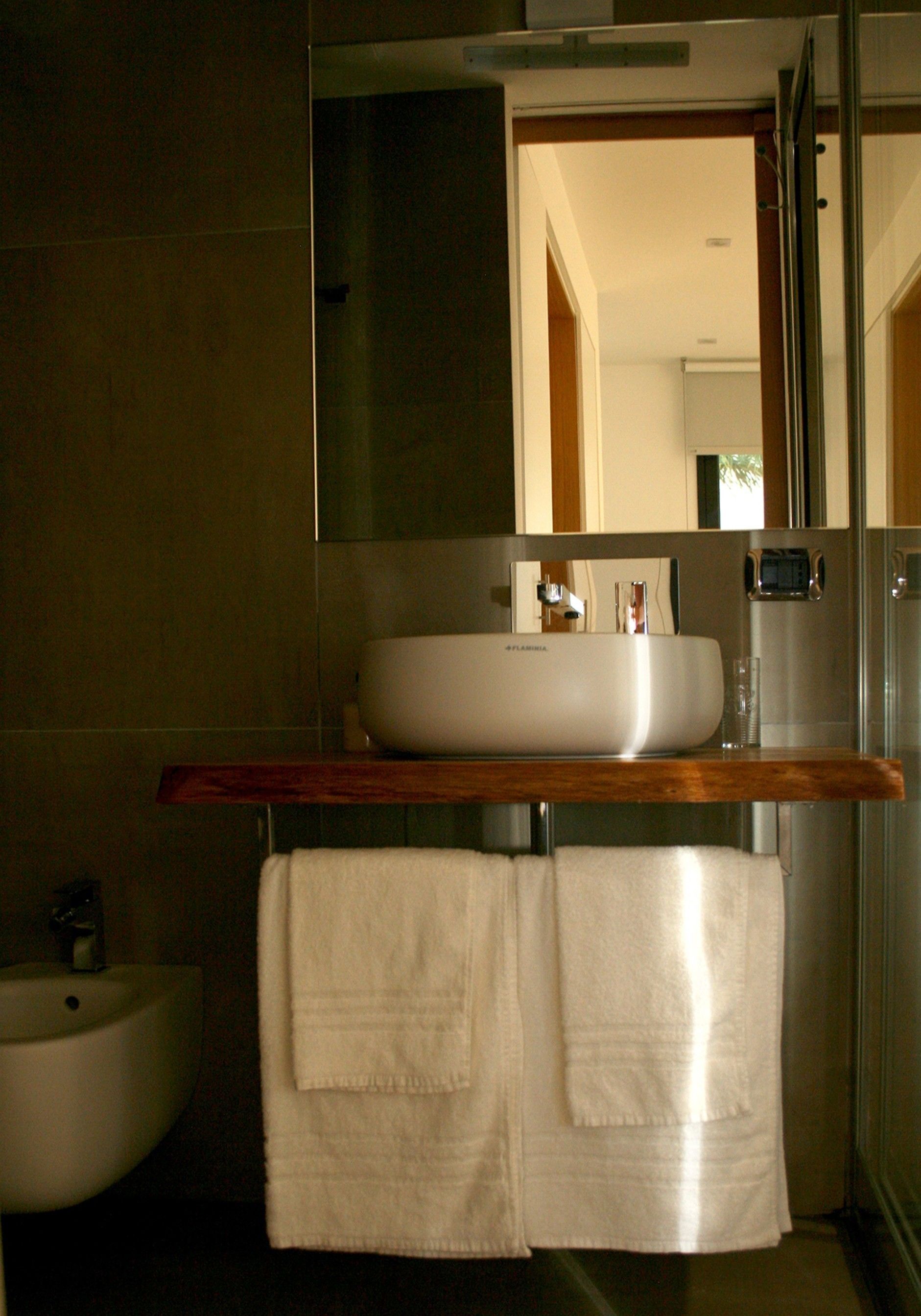 A bathroom with a modern sink, a mirror, and a towel rack.
